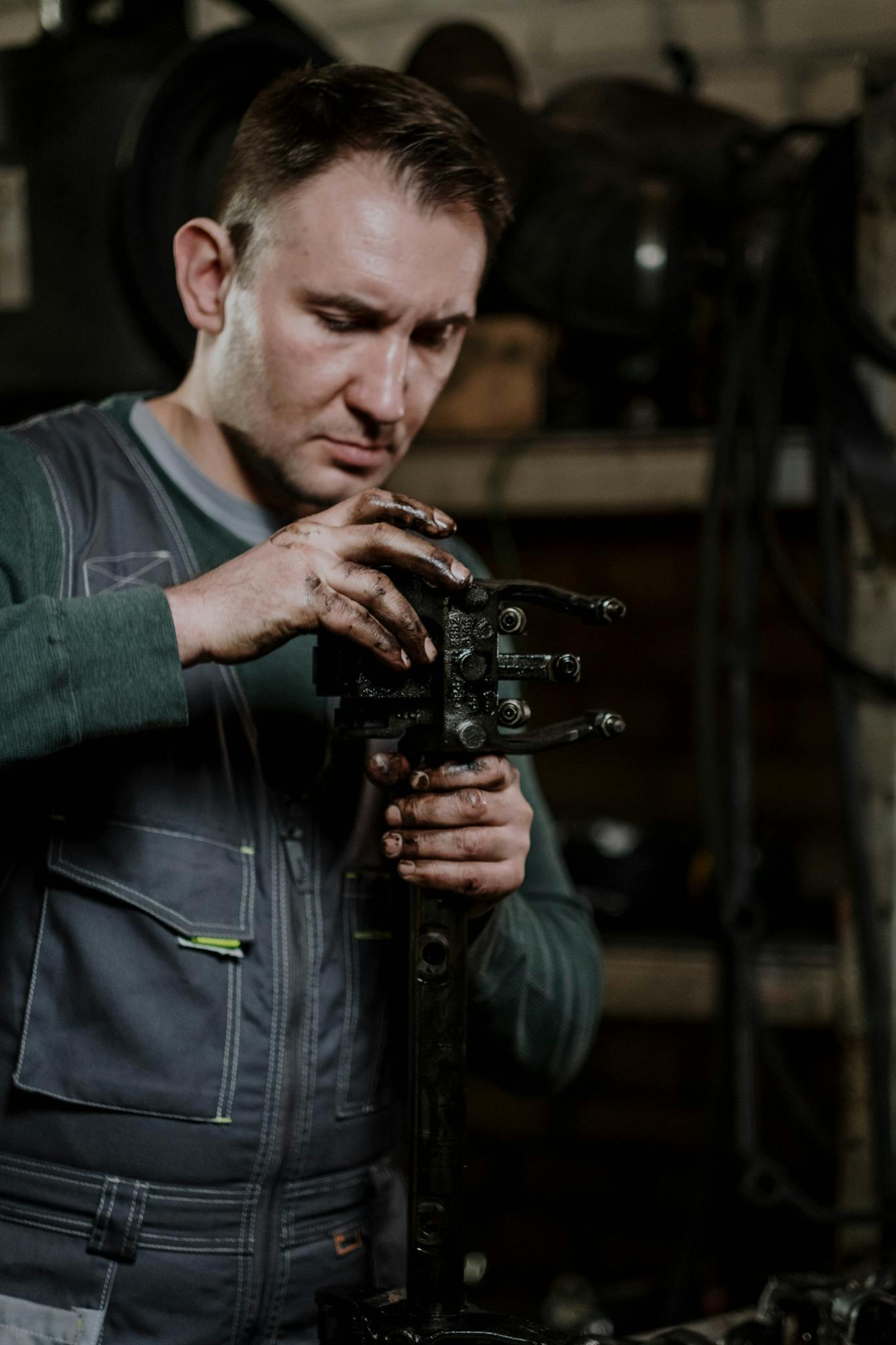 A mechanic focused on repairing a car component in a dimly lit workshop, demonstrating technical expertise and mechanical skill.